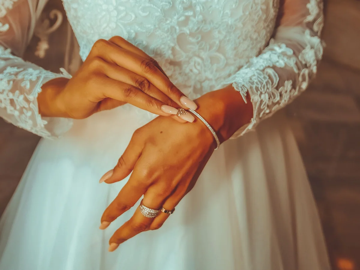 Woman planning wedding-guest outfits with accessories on a bed